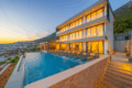 Villa Falcon Grey in Kalkan with private infinity pool, modern three-story architecture, luxury sun loungers, and panoramic sea and mountain views at sunset