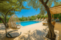 Villa Husam Kalkan – outdoor private pool surrounded by olive trees, sun loungers, and a relaxing hanging chair in a lush Mediterranean garden.