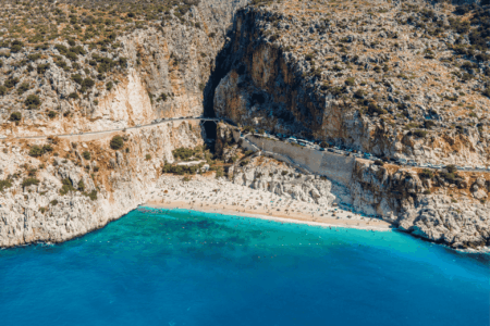 Aerial view of Kalkan Beach with turquoise waters, sunbeds, and the scenic Mediterranean coastline in Turkey