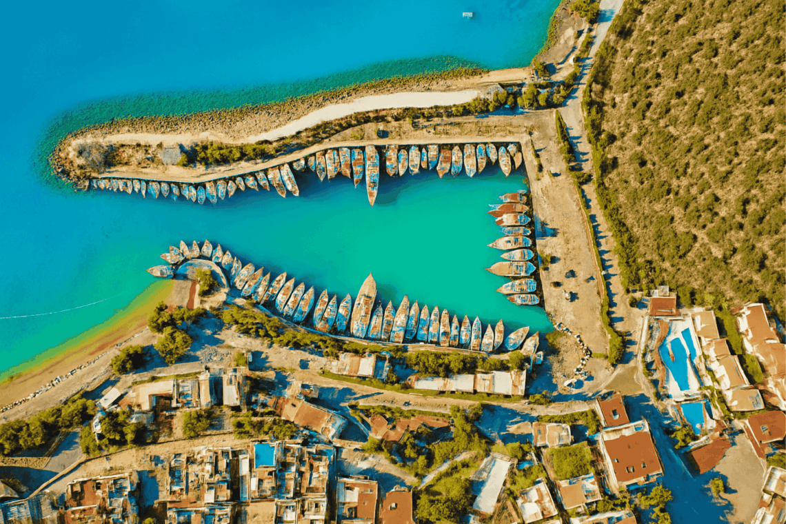 Aerial view of Kalkan harbor with turquoise Mediterranean waters, boats, and surrounding coastal town, Turkey.