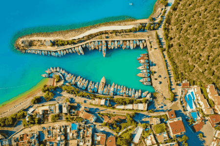 Aerial view of Kalkan harbor with turquoise Mediterranean waters, boats, and surrounding coastal town, Turkey.